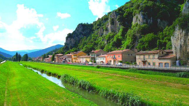 Wonderful aerial push-in shot from Pioraco, drone hanging low to capture the light-mirroring, specular reflecting, lucent glowing waters of the Potenza river flanked by gorgeous greenery and Sibillini