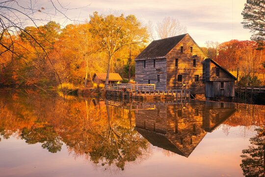 A nice Autumn landscape of the Yates Mill reflecting in the water at the historic Yates Millpond Park in North Carolina USA.
