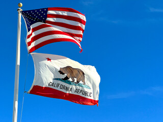 Closeup of American and Californian Flags Waving on a Windy Day with Blue Sky. California, United...