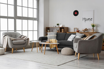 Interior of living room with black sofa, armchairs and tables