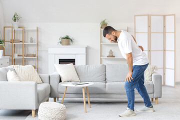 Young man suffering from back pain at home