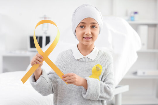 Little girl after chemotherapy with yellow ribbons in clinic. Childhood cancer awareness concept - Powered by Adobe