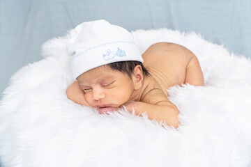 Newborn photography at home sleeping newborn baby  photo shoot. baby boy sleeping  with cap and two...