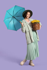 Stylish young woman with chrysanthemum flowers and umbrella on lilac background