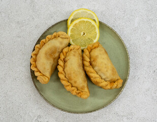 Traditional south american food. Top view of three fried meat empanadas with lemon in a dish with a...