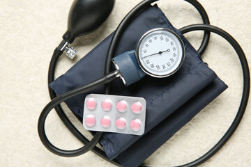 Blood pressure measuring device and pills on light textured background, top view