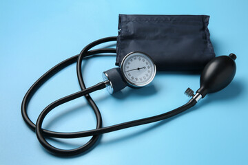 Blood pressure measuring device on light blue background, closeup