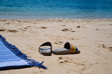 part of a bedspread and flip-flops on a sandy beach near the ocean. High quality photo