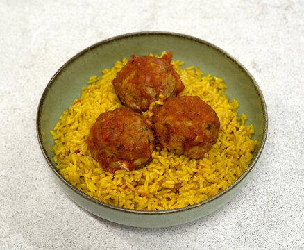 Traditional mediterranean dish. Top view of hake fishballs with tomato sauce and rice with saffron, in a bowl  with a white background