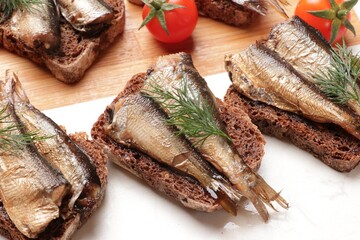 Delicious sandwiches with sprats, dill and tomatoes on table, closeup