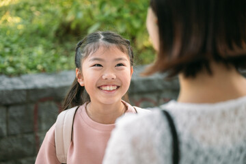 Smiling asian student girl with backpack talking to her teacher in a school park in Tokyo Japan