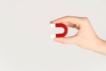 Woman with horseshoe magnet on light background, closeup. Space for text