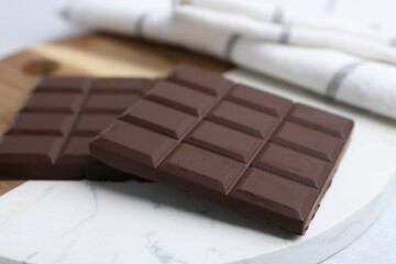 Pieces of delicious dark chocolate bar on light table, closeup