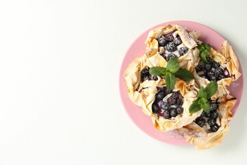 Tasty puff pastries with blueberries, powdered sugar and mint on white table, top view. Space for text