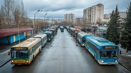 Obraz premium A row of parked buses on a city street under a cloudy sky.