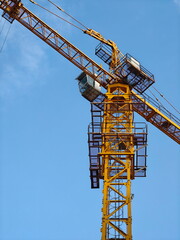 Naklejka premium Tower crane under a clear blue sky at a construction site in an urban area