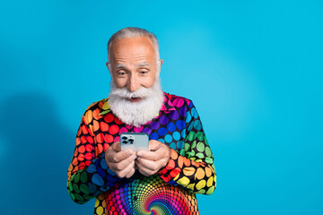 Portrait of funny extravagant aged man use phone empty space wear shirt isolated on blue color...