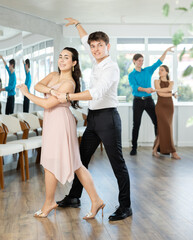 Couple in festive clothes learn to dance latin american dance bachata in studio