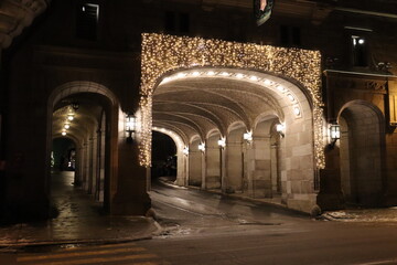 Obraz premium Beautiful outdoor lights in an entrance and Christmas time. Old architecture and entrance. An evening scene in december with an outdoor lighting. Quebec history and an ancient ceiling of an entrance. 
