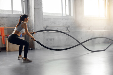 An enthusiastic fitness lover is engaged in an intense battle rope workout at a vibrant and...