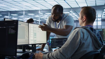 Engineer having fun with colleague at work in data center establishment, making jokes. Team of...
