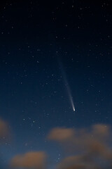 Comet glowing in a starry night sky with clouds