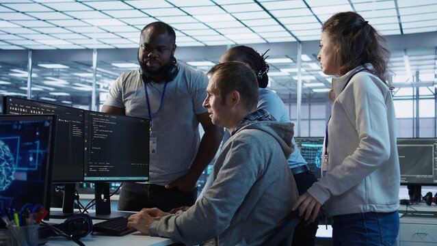 Technician doing brainstorming with colleagues to fix error in code affecting server room AI workloads. Team of artificial intelligence engineers repairing data center systems together, camera B