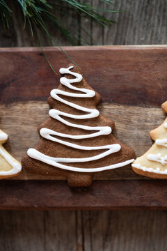 Decorated gingerbread tree-shaped cookie on wooden board
