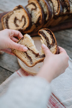 Hands breaking a slice of chocolate swirl bread