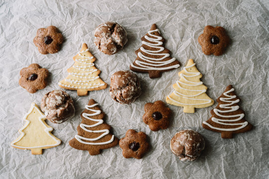 Baked holiday cookies with icing on crumpled paper.