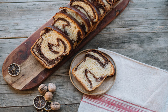 Chocolate swirl bread slices on wooden board with nuts
