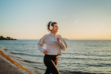 Young caucasian woman running or jogging on the beach at sunset	