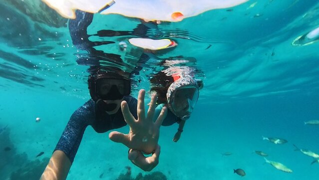 Family snorkeling with fish in Maldives