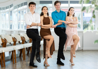 Group of young men and women dancing folk dance in row in studio