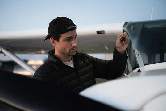 Pilot of a small aircraft checking the engine oil level before flight