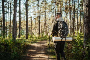 Naklejka premium Young caucasian man hiking or trekking through the forest 