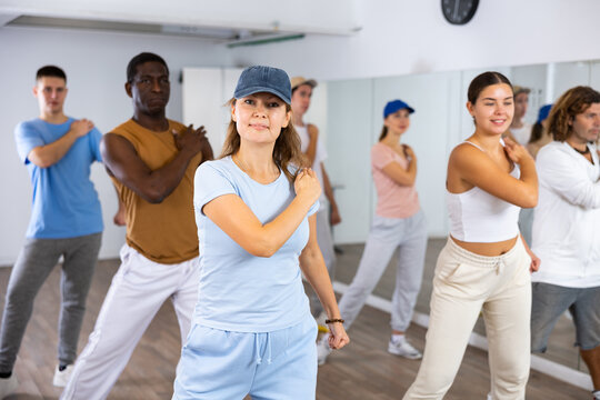 Excited sporty multiracial people practicing new movements steps during dancing training in studio