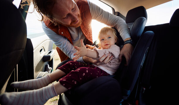 Man settles his little daughter into the seat
