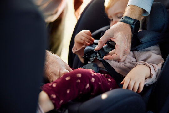 Man fastens kid in the safety car seat