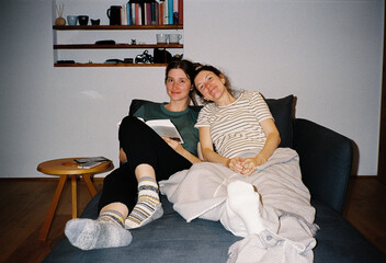 Smiling sisters sitting together on a sofa at home
