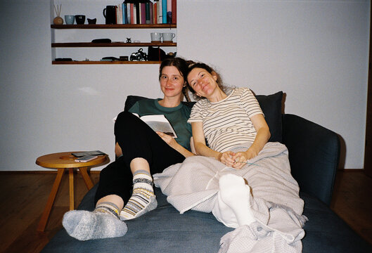 Smiling sisters sitting together on a sofa at home