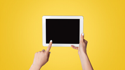 Millennial woman touching empty screen of tablet device on light background, close up. Space for design
