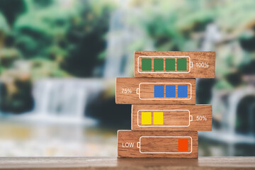 Battery charge indicator on wood block with blurred nature waterfall background . For wellness,...