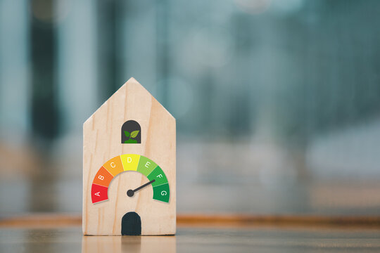 For house energy efficiency, eco home renovation save cost. Low consumption ecological house, Sustainable Development Concept, house with energy efficiency scale on blurred background..