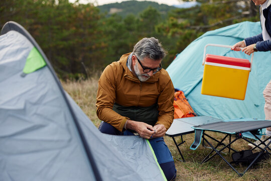Man sets up a tent in a camp
