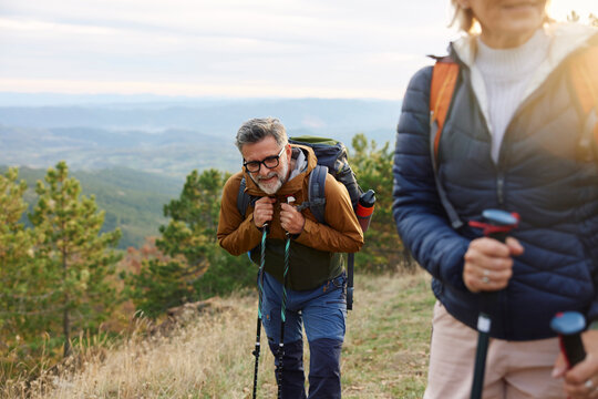 Mountaineer rests leaning on hiking poles