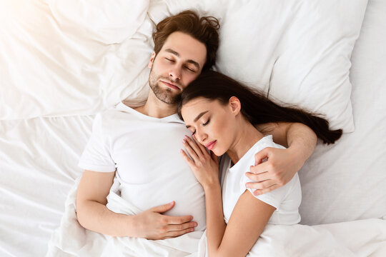 Married Couple Sleeping Together Embracing Lying In Comfortable Bed At Home At Night. Top View Shot Of Spouses Resting Peacefull Enjoying Nap In Comfortable Bedroom