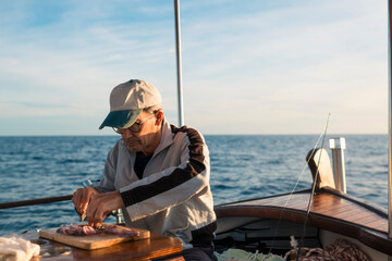Focused fisherman preparing squid bait on boat