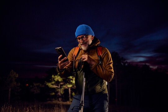 Cheerful hiker looking at his phone