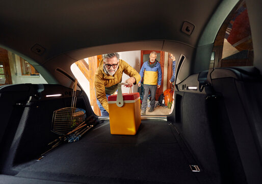 Man packs camping stuff in the back of a car